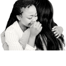 Two young women hug each other. On the left, a girl with braids holds a tissue to her nose and looks like she is crying. On the right, only the back of the second girl's head is visible. She has long, dark hair that covers most of her back.